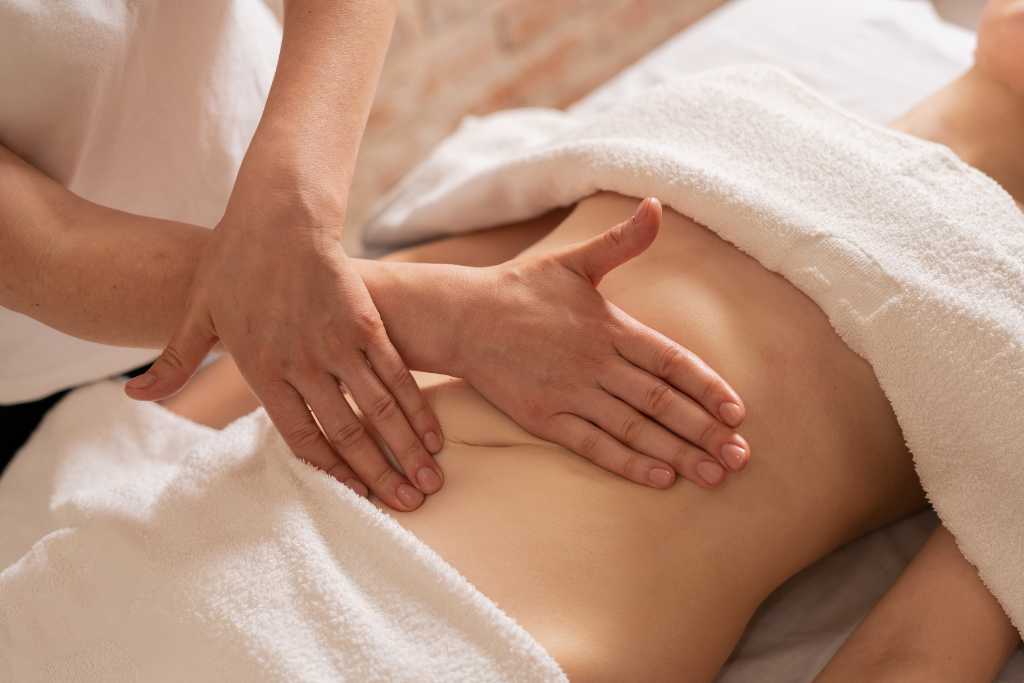 Massage therapist performing abdominal massage for digestion and relief