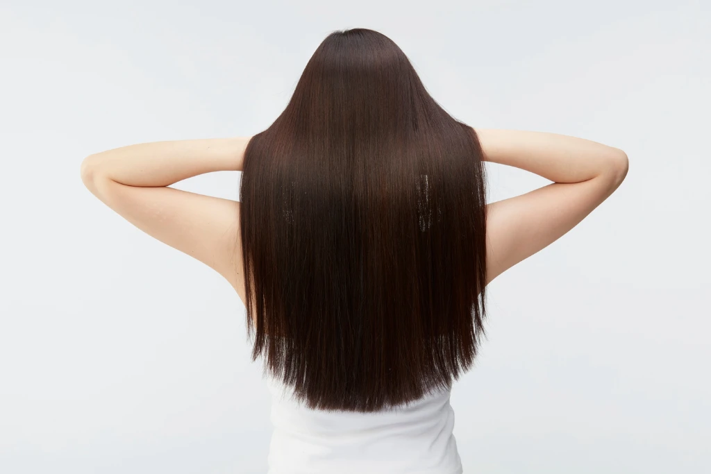 Rear view of a woman with long, straight, and shiny dark brown hair that looks healthy and smooth against a clean white background.