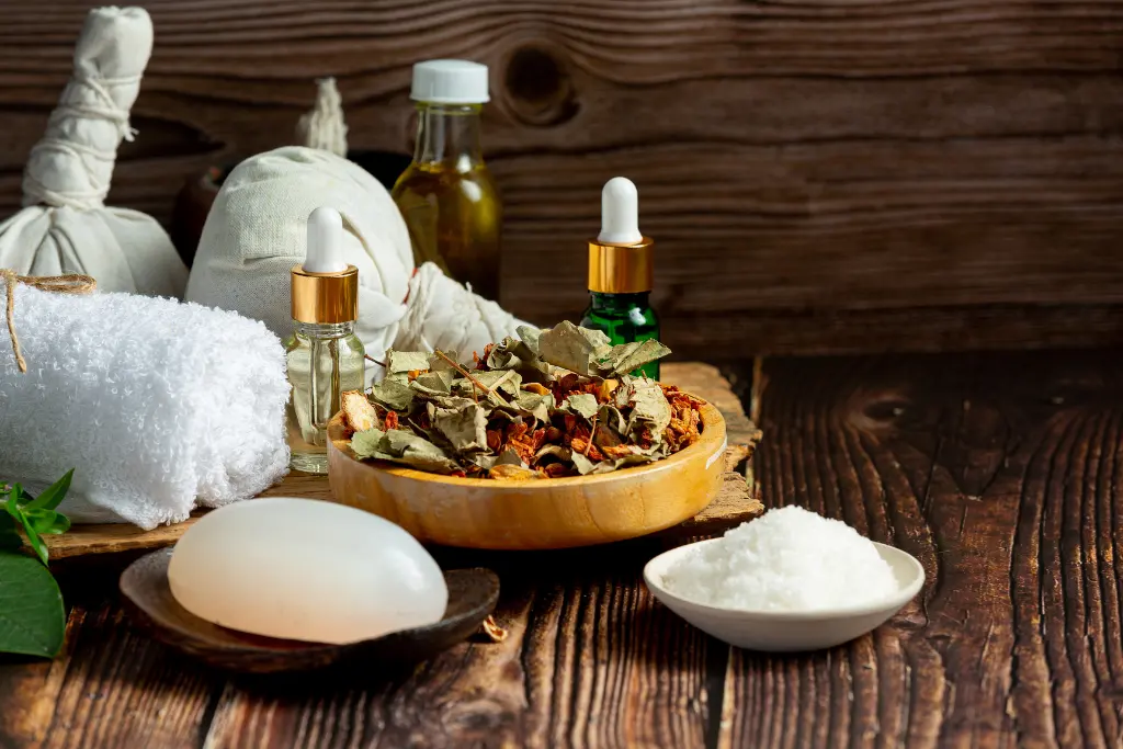 A close-up, authentic photograph of a natural head massage oil in a glass dropper bottle, surrounded by herbal ingredients on a dark wooden background.