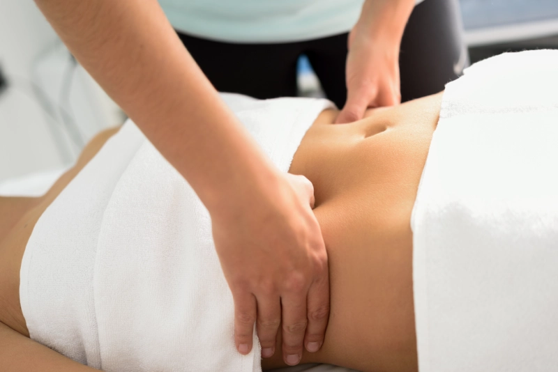 Hands massaging female abdomen therapist applying pressure belly